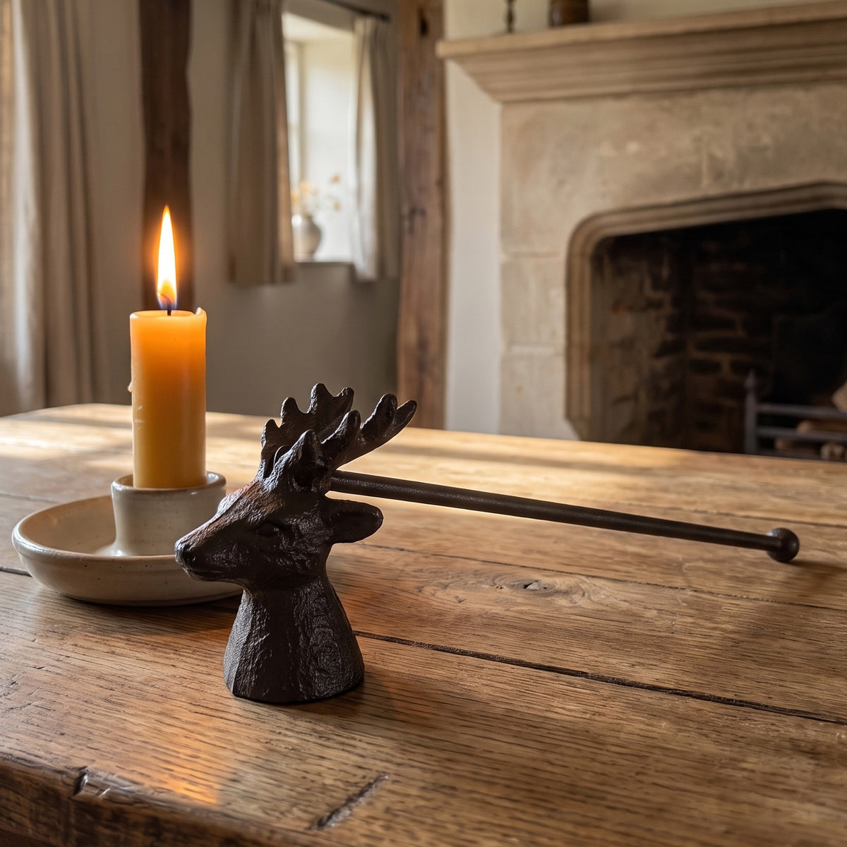 Stag candle snuffer beside a candle on a farmhouse wooden table