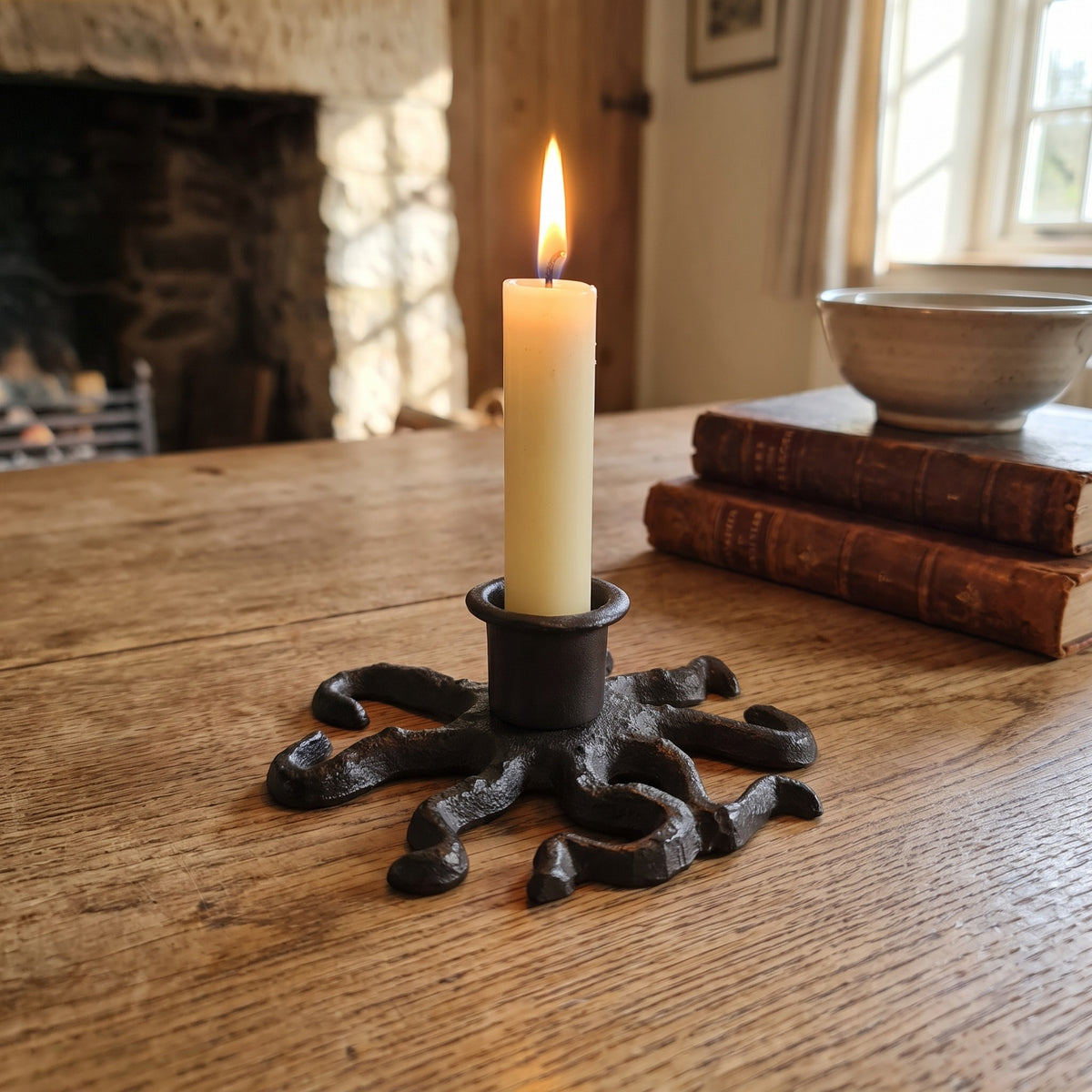 Octopus candle holder with a lit taper candle on a rustic wooden table