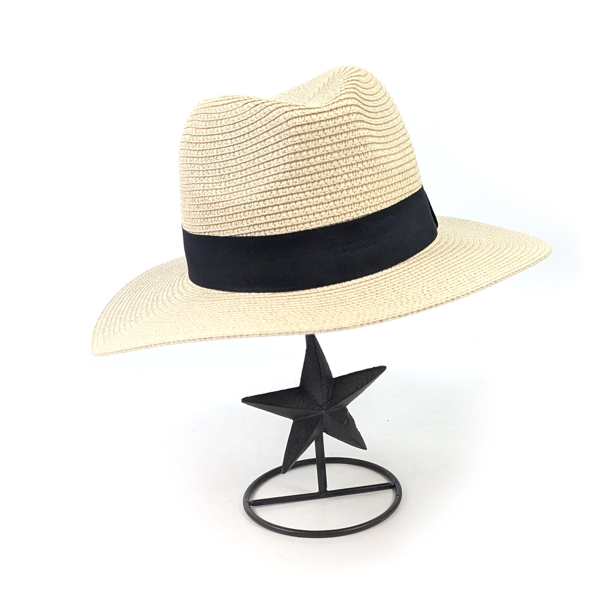 Cast iron star hat stand holding a cream hat with a black band