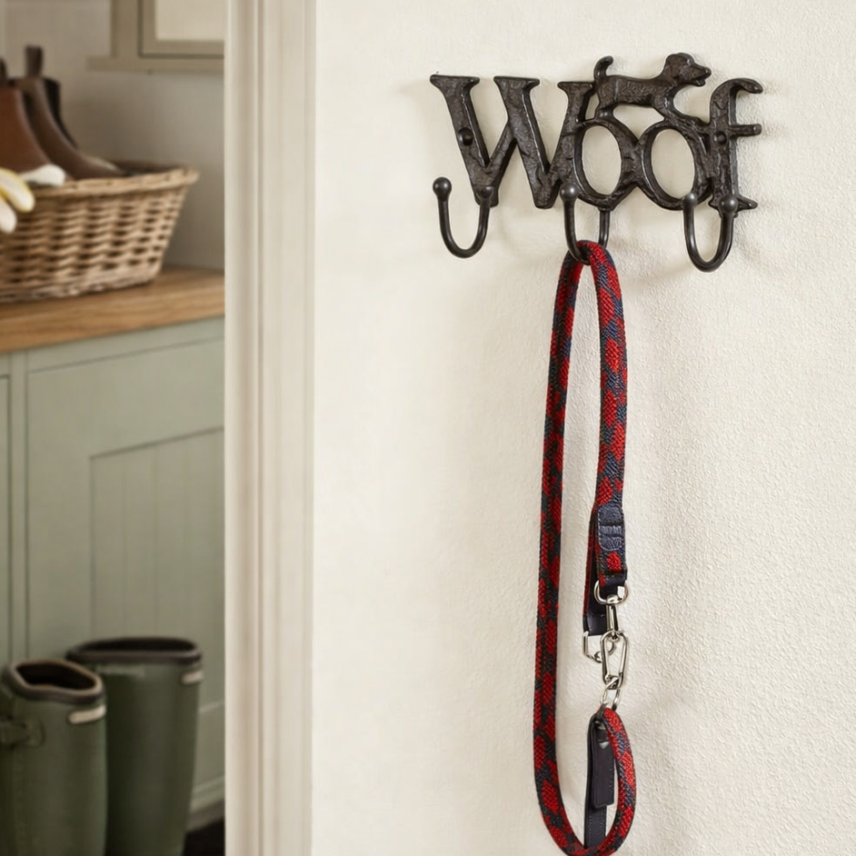 Decorative wall hook with 'WOOF' design holding a dog leash in a home setting.