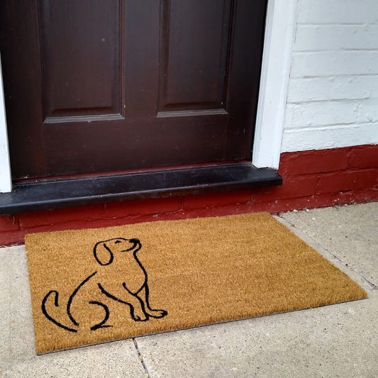 A brown coir door mat with a black silhouette of a dog design in the center.